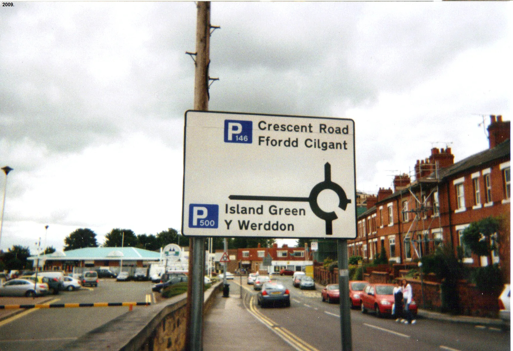 I took this picture of a Welsh language road sign near Wrexham Central railway station myself in the year 2009. I hereby release it into the public domain.