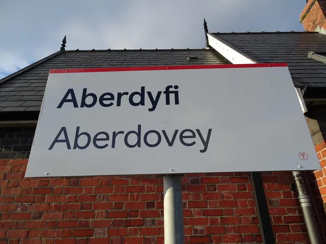 Signboard at Aberdovey railway station in Gwynedd, Wales. The grey text is typically used on bilingual signs where the English language name of the station is different to the Welsh name in Wales since Transport for Wales replaced, in c.2023, the previous signs with green and black text that were in. Questions UK brands should ask a bilingual social media agency